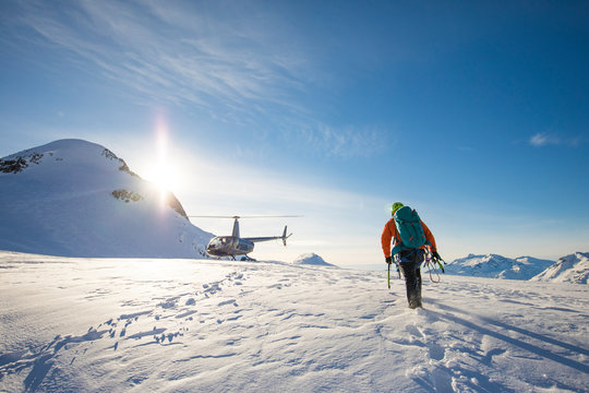 Mountaineer approaches his chartered helicopter, waiting on a glacier