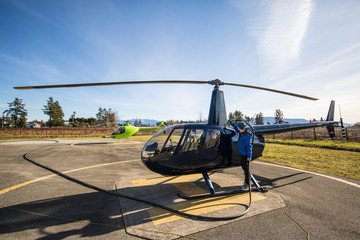 Helicopter pilot fueling his helicopter, parked on helipad