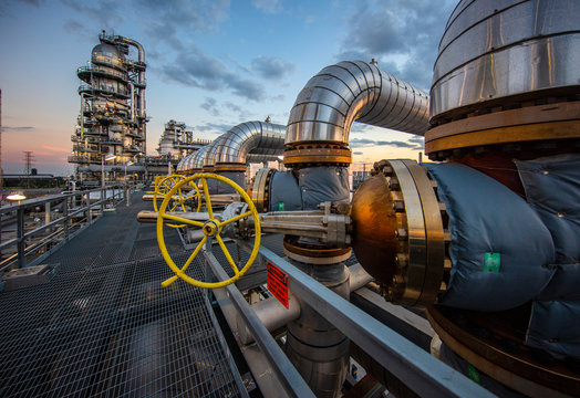 Sunset as viewed through pipe and vales in refinery