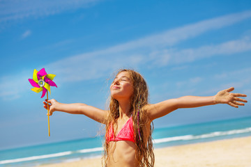 Girl with pinwheel on the beach happy and relaxed
