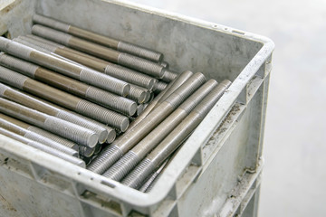 metal threaded studs lie in a plastic box