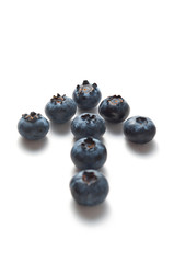 Blueberries are laid out on a white background in the form of an up arrow.