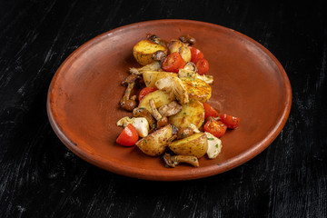 Fried potatoes with mushrooms on a beautiful clay plate.