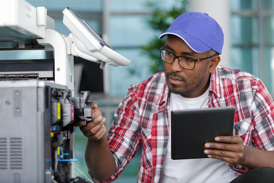 Serviceman With Tablet Repairing Office Photocopier