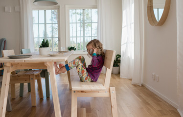 Young girl sat at the table using a mobile phone at dinner time