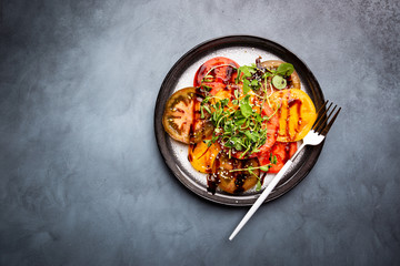 Fresh colorful tomatoes salad with balsamic vinegar on a plate, top view