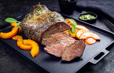 Traditional roasted beef heart with fried pumpkin slices and chimichurri sauce as closeup on a...