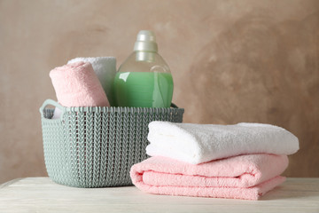 Obraz na płótnie Canvas Basket with clean towels and laundry liquid on wooden background, space for text