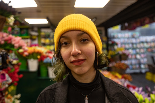 Portrait of young woman in yellow hat standing in florist