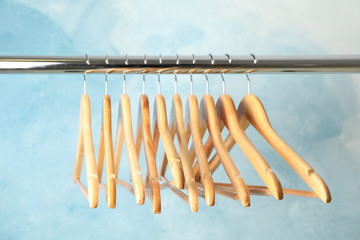 Hangers on rod against blue background, space for text