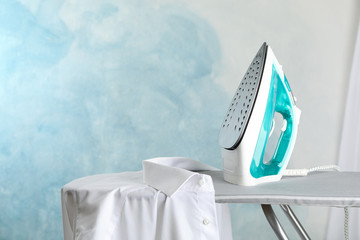 Iron and shirt on ironing board, space for text
