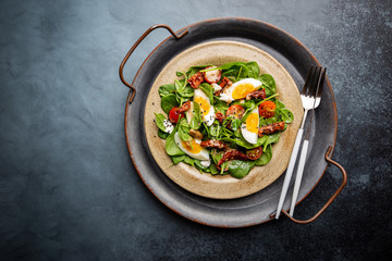 Salad with spinach, sun-dried tomatoes and eggs. Healthy home made food. Concept for a tasty and healthy meal. Top view. Copy space.