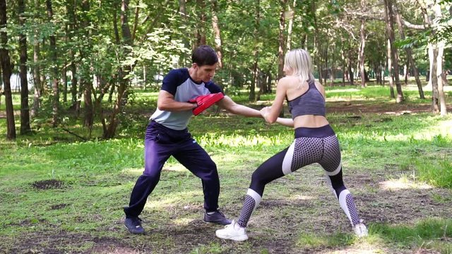 A woman with a trainer fulfills self-defense techniques, slow motion.