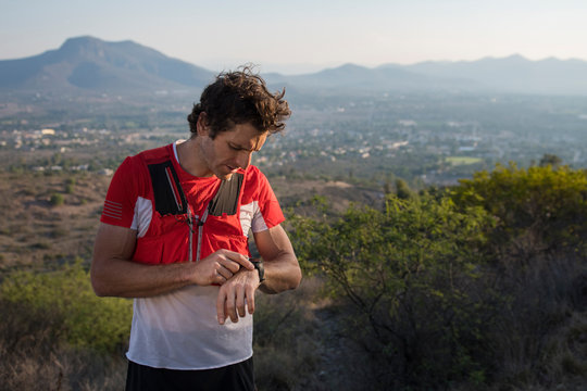 Male trail runner looks at his watch at sunset in mountains of el Arenal, hidalgo, Mexico