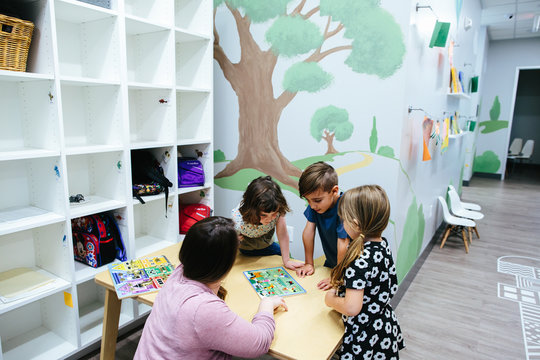 Three students gather around a table with their teacher