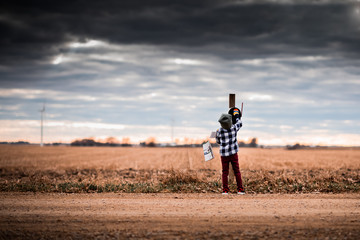 A small boy getting mail from a mailbox on a dirt road