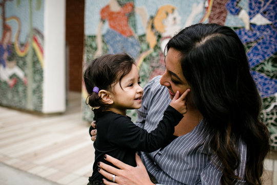Mother and daughter looking at one another in front of mural