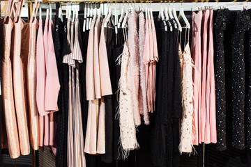 Close-up view of various stylish clothes hanging on hangers in boutique. Clothes