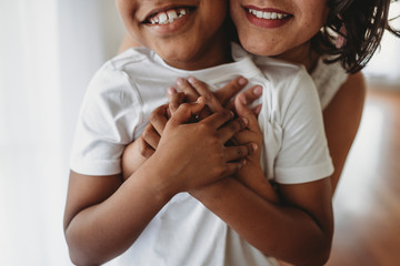 Close up view of intertwined hands as mother embraces son