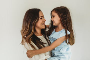 Mother and daughter looking at each other and smiling in studio