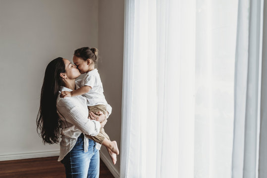 Young mother with long hair holding toddler boy and kissing in studio