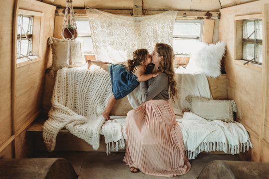 Mother and daughter kissing in boho studio setup