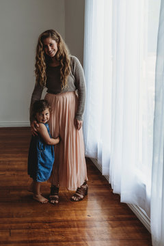 Full length portrait of mother and daughter smiling at camera in studio