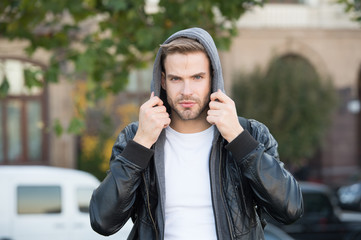 Hooded and protected. Handsome man unshaven face and stylish hair. Caucasian man urban background....