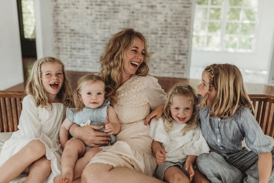 Mother and daughters looking at each other lovingly on studio couch