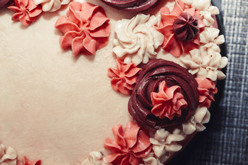 Naklejka na ściany i meble Pink cake with cream flowers on a dark background