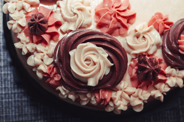 Pink cake with cream flowers on a dark background