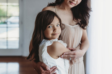 Mid level view of school aged girl being hugged by mother