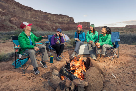 A group of women sit by a campfire in the desert