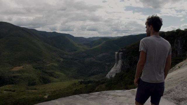 SLOW MOTION - Over the shoulder shot tracking tourist walking to edge of Hierve El Agua Rock Pool in Oaxaca, Mexico