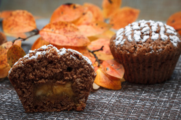 Chocolate muffins with apple filling on a background of autumn leaves and cinnamon
