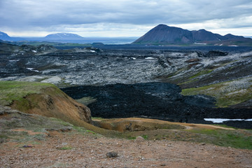 Leirhnjukur old black lava field with colorful stones  and blue sky in Iceland, overcast day in...