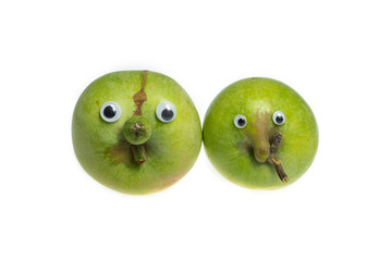 Trendy ugly food concept. Two green funny apples with eyes isolated on white background. Fruit with...