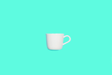 White cup for coffee on mint green blue color.