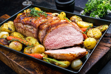 Traditional roasted dry aged veal tenderloin with carrots and potatoes offered as closeup on a metal tray - obrazy, fototapety, plakaty