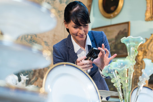 woman photographing antique objects on display