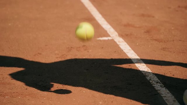 Shadow silhouette of tennis player bouncing ball and serving, slow motion.