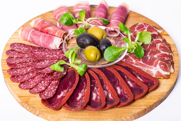 Food tray with delicious salami, pieces of sliced ham, sausage and olives. Meat platter.