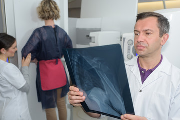 female having xray in standing position doctor studying results