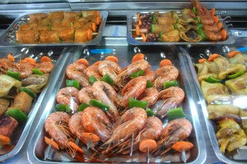 Giant shrimps prepared for grilling, in the background skewers of different species of fish