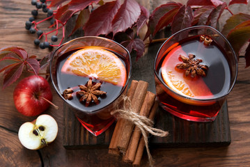 Mulled wine with citrus fruits and spices. Couple wineglass of winter grog with orange, cinnamon and anise