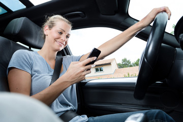 Obraz na płótnie Canvas woman driving and texting on cell phone