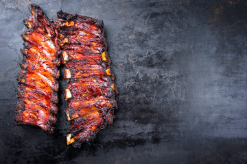 Barbecue burnt chuck beef ribs with hot marinate as top view on an old rustic board with copy space right © HLPhoto