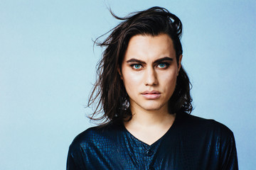 Portrait of a young man with  make up and long hair in studio