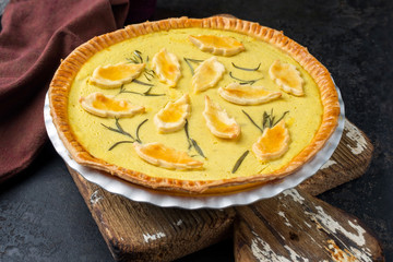 Traditional French Autumn pumpkin tarte offered as closeup in a backing form on an old wooden cutting board