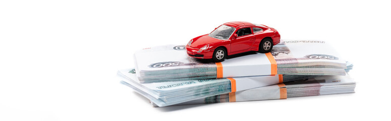 panoramic shot of red toy car on stacks of russian money isolated on white